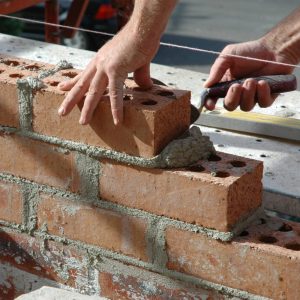 Brick wall being built using mixed mortar